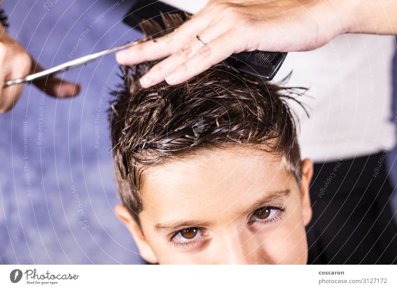 Beautiful boy getting a haircut with scissors - a Royalty Free Stock Photo  from Photocase