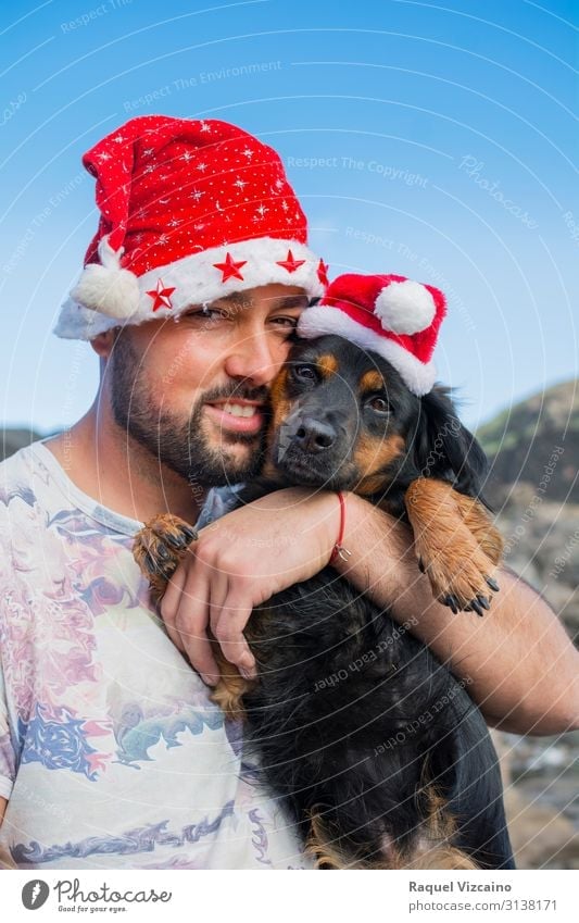 Man and his dog with Christmas hats. Joy Winter Christmas & Advent Adults Friendship 1 Human being 30 - 45 years Animal Hat Pet Dog Love Cute Blue Red White