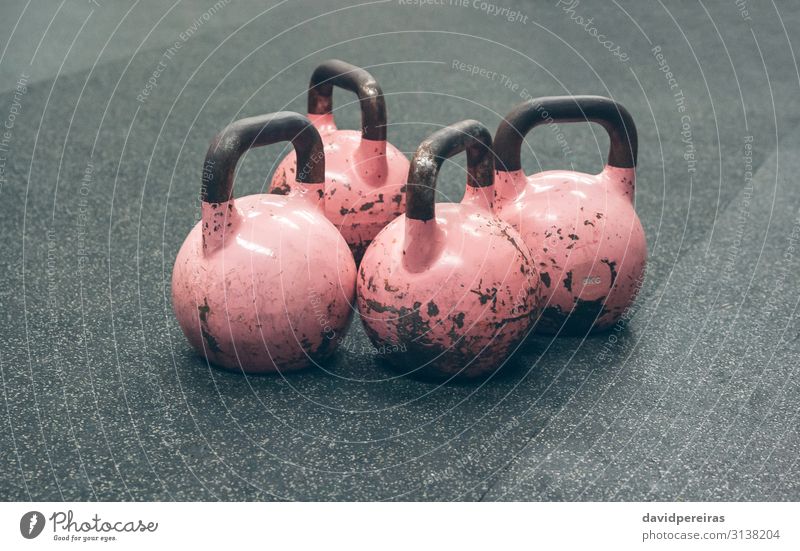 Kettlebells on the floor of a gym Sports Pink kettlebell Gymnasium box weights four Second-hand cross fit isolated kettle-bell Worn out chipped Story Horizontal