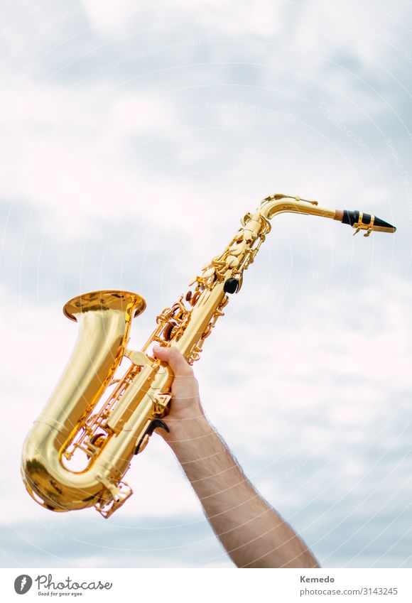 Hand holding saxophone with cloudy and soft sky background. Lifestyle Design Joy Beautiful Wellness Harmonious Leisure and hobbies Freedom Music Success