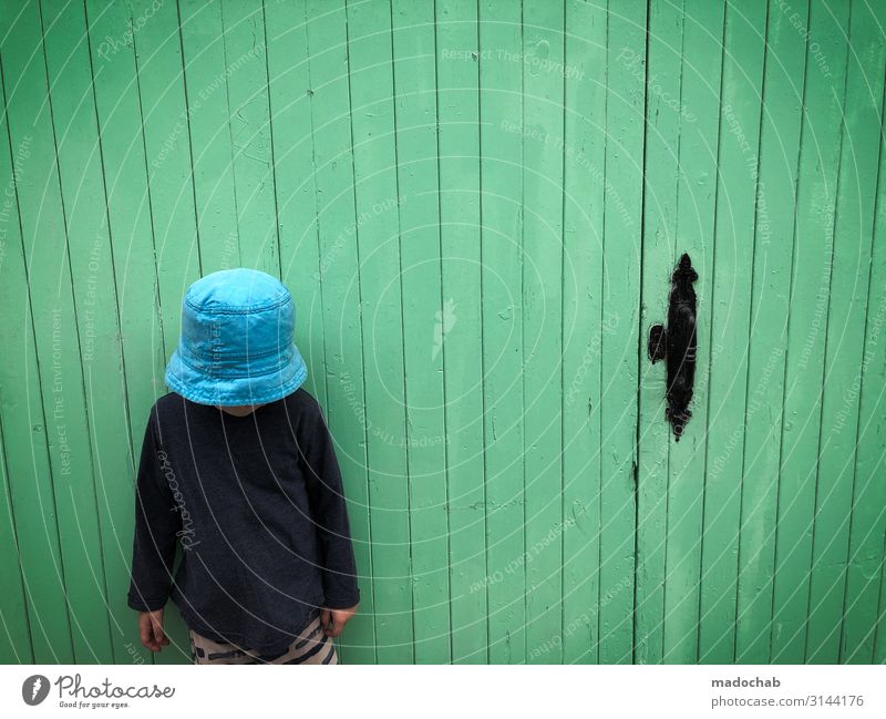 Camera view - boy stands in front of green wall Text space Toddler Boy (child) Life Wall (barrier) Wall (building) Facade Door Cap Moody Secrecy Esthetic