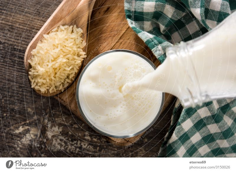 Pouring rice milk in glass on wooden table. Top view Rice Milk water Beverage calcium Fluid Liquid Food Healthy Eating Food photograph Glass Nutrition Natural