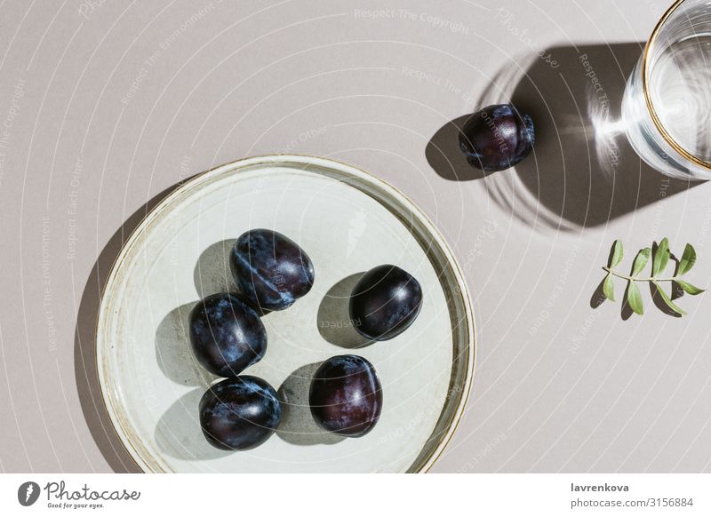 Minimalist flatlay of plums on a handmade plate and water Branch Delicious Dessert Diet Eating Food Healthy Eating Fresh Fruit Gray Juicy Leaf Minimalistic