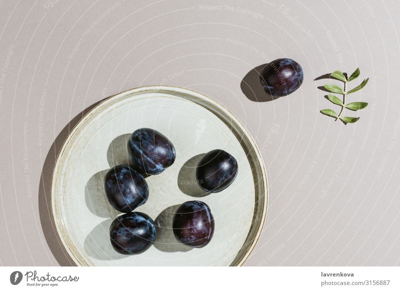 Minimalist flatlay of plums on a handmade plate Diet Minimalistic Branch Leaf Plum Neutral Gray Juicy Nutrition Eating Summer Nature Raw Dessert Tasty Delicious