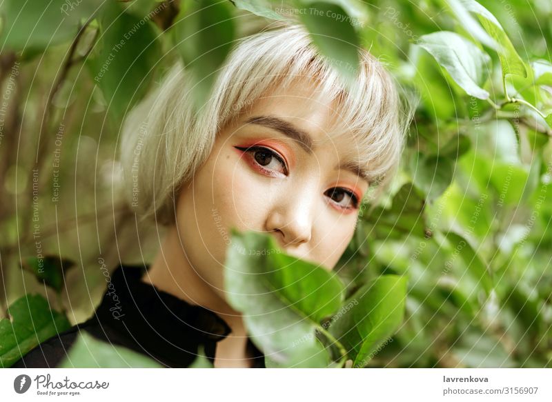 Asian female in green leaves, shallow selective focus Tree Spring Garden Summer Asians Blonde Close-up Cute Eyes Face Woman Young woman Greens kawaii Leaf