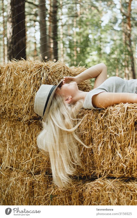 Blond woman in a hat lying hay stack, selective focus Young woman Happy Festive Park Forest Attractive Village Landscape Covering Hat Blonde Caucasian Nature