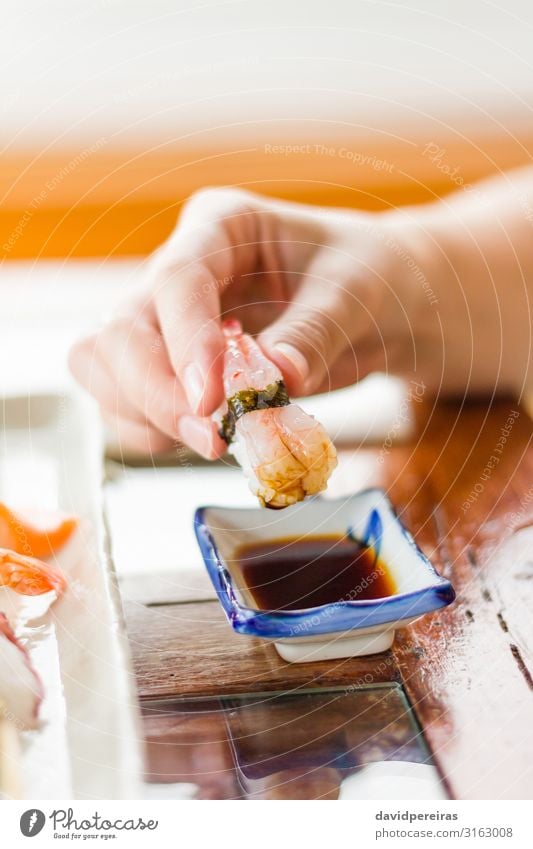 Hand girl dipping a piece of sushi on soya sauce Dinner Sushi Plate Tradition Asia assortment bonito Cooking Dish eat fillet fish ginger Gourmet japanese Meal