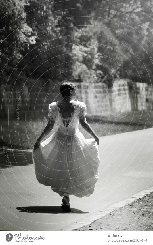 Woman in nostalgic wedding dress strides on sunny paths, back view Bride Wedding dress Feminine Adults Lanes & trails long dress Short-haired Going Funny Joy