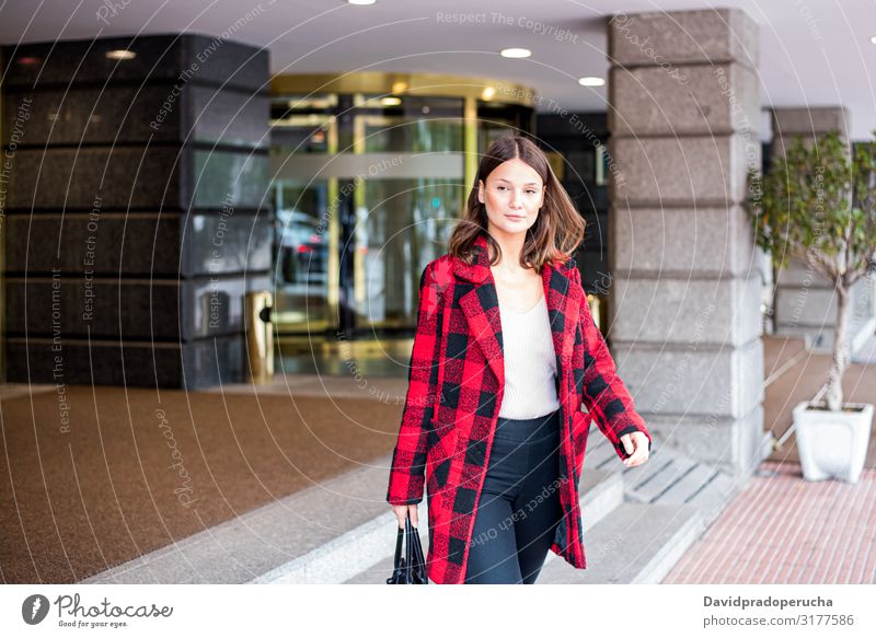 pretty young woman walking leaving an Hotel wearing autumn elegant clothes street smile daylight looking away outdoors city cheerful horizontal one person girl