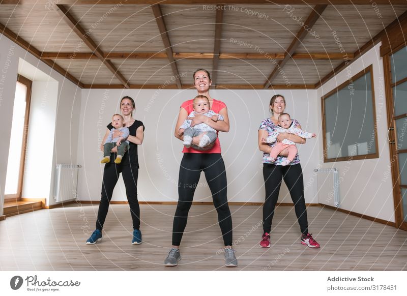 Mothers lifting babies in gym Baby Gymnasium Practice Lift workout Fitness Modern Lifestyle Woman Child Happy Smiling Cheerful Joy Sportswear Group Playing