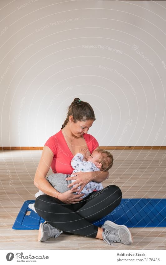 Mother feeding baby in gym Feeding Baby Gymnasium Breasts Fitness Sports Woman workout Child Suck Milk Story Sit Smiling Cheerful Happy Lifestyle