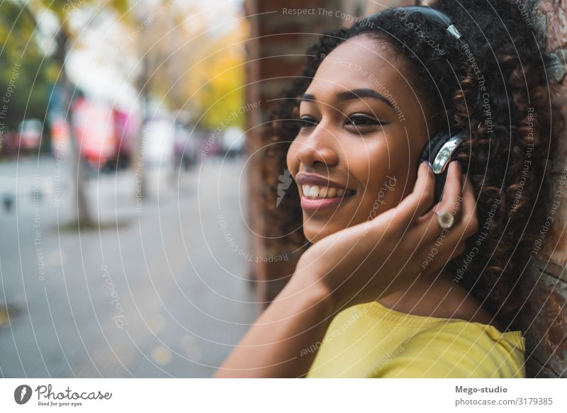 Afro american woman listening music Lifestyle Style Joy Relaxation Leisure and hobbies Entertainment Music Woman Adults Street To enjoy Listening Smiling