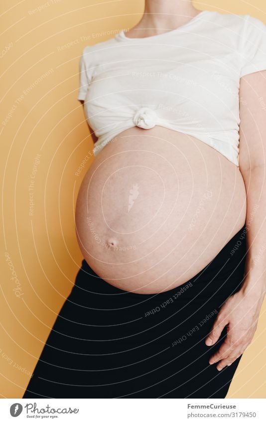 Pregnant woman showing her baby belly - neutral background Feminine Woman Adults 1 Human being 18 - 30 years Youth (Young adults) 30 - 45 years Happy Baby bump