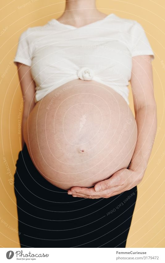 Pregnant woman showing her baby belly - neutral background Feminine Woman Adults 1 Human being 18 - 30 years Youth (Young adults) 30 - 45 years Happy