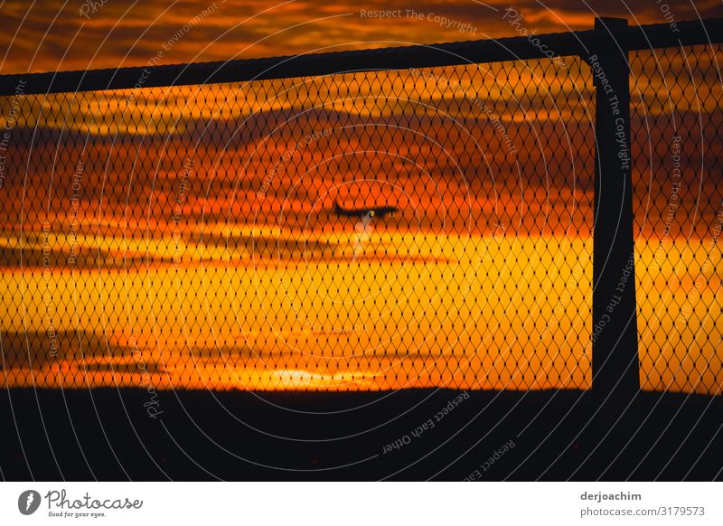 In the approach there is an aircraft in the dawn. Taken behind a grid barrier with a pole. Joy Relaxation Trip Services Aviation Environment Sunrise Sunset