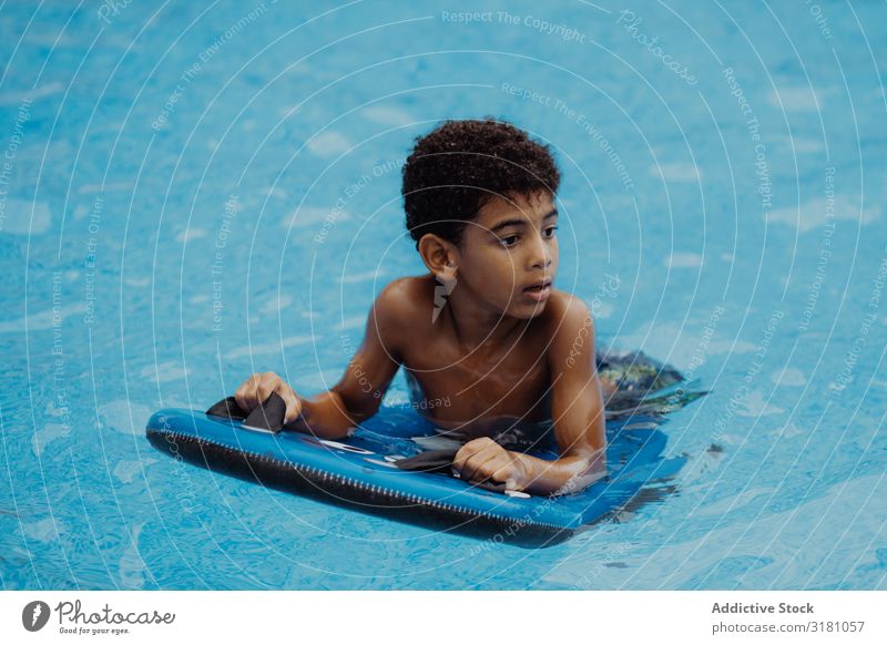 Black boy swimming in pool Boy (child) Swimming pool Looking away Summer Happy Joy Water Vacation & Travel Child African-American Ethnic Inflatable Relaxation