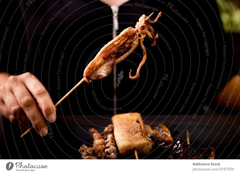 Woman eating grilled squid skewer in restaurant Grill Impaled Squid Food Meat Vegetable shish Café Restaurant Eating Dish Meal Nutrition To feed Lunch Dinner