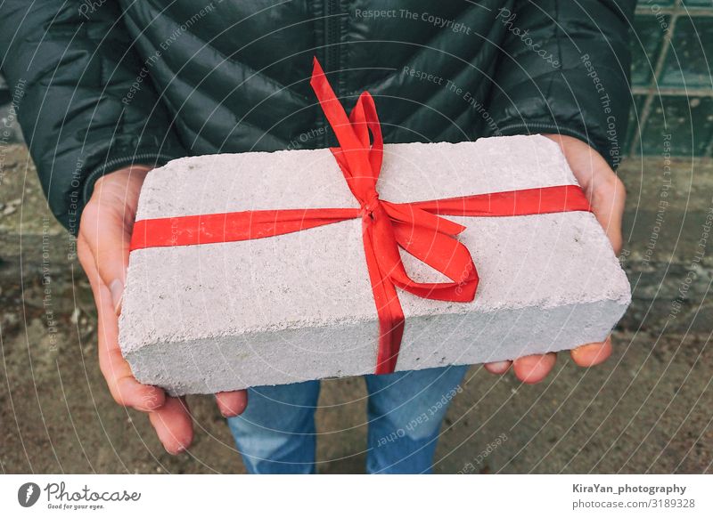 White brick with red ribbon as gift box Lifestyle Shopping Design Joy Leisure and hobbies Decoration Christmas & Advent Birthday Hand 1 Human being Package Box