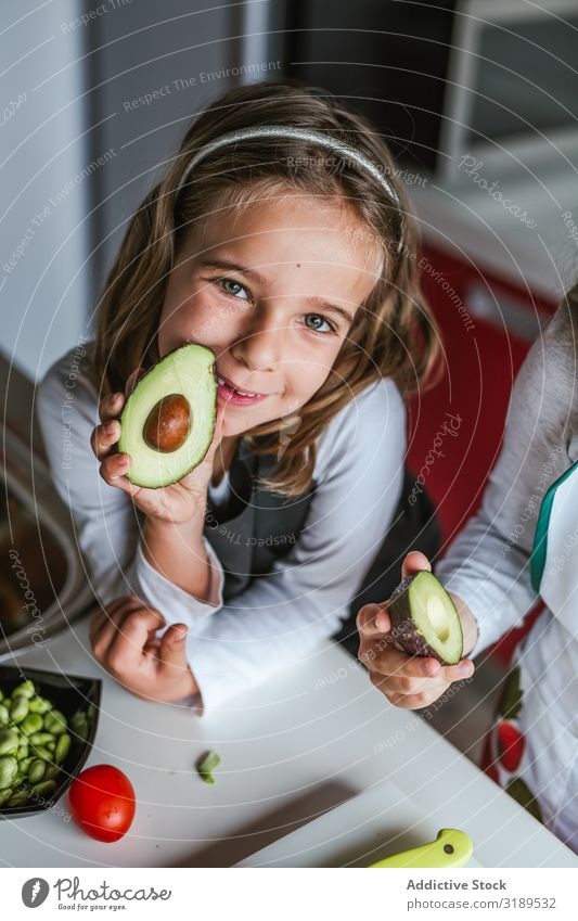 Little girl showing cut avocado Girl Indicate Half Avocado Kitchen Mature Child Cooking Healthy Diet Home Woman Seed Food Green Vegetarian diet Oily Fresh