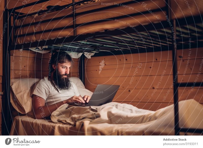 Man using laptop in rustic bunk bed Notebook Rustic Hipster Work and employment freelance bearded Wood House (Residential Structure) concentrated Technology