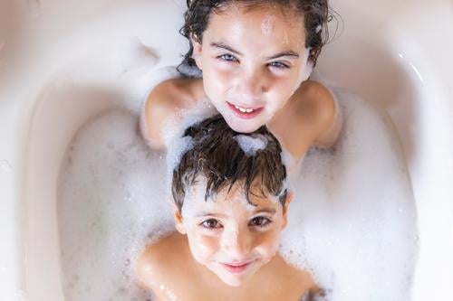 Two kids taking a bath looking a camera Lifestyle Joy Happy Beautiful Personal hygiene Body Skin Well-being Swimming & Bathing Bathtub Bathroom Child