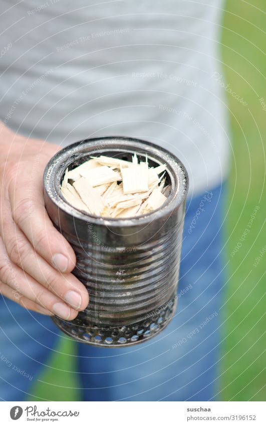 hand holding a tin can with wood shavings | hobo cooker Man by hand Fingers Tin Wood shavings start a fire Quiver hobo oven Camper Camping cooker Can cooker