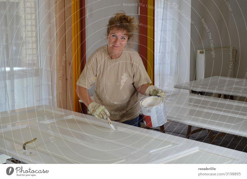 blonde woman paints carefully old door panels with white lacquer - do it yourself Joy Leisure and hobbies Flat (apartment) Redecorate Work and employment