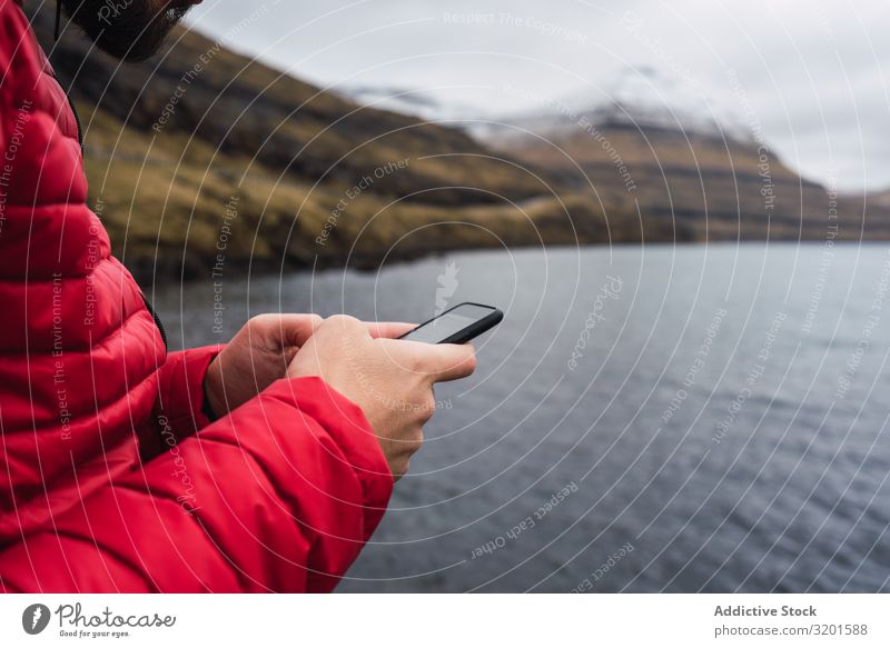 anonymous man using smartphone near a lake in Faroe Island River Green Human being White Telephone Hold over Cellphone messaging Communication Smart Natural