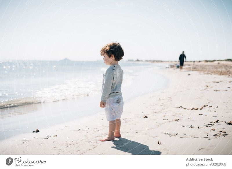 Barefoot child in short watching waves on sandy beach Child Small Sand Wave Beach babyhood Cute Joy exploring Beautiful Cheerful Infancy Discovery pretty