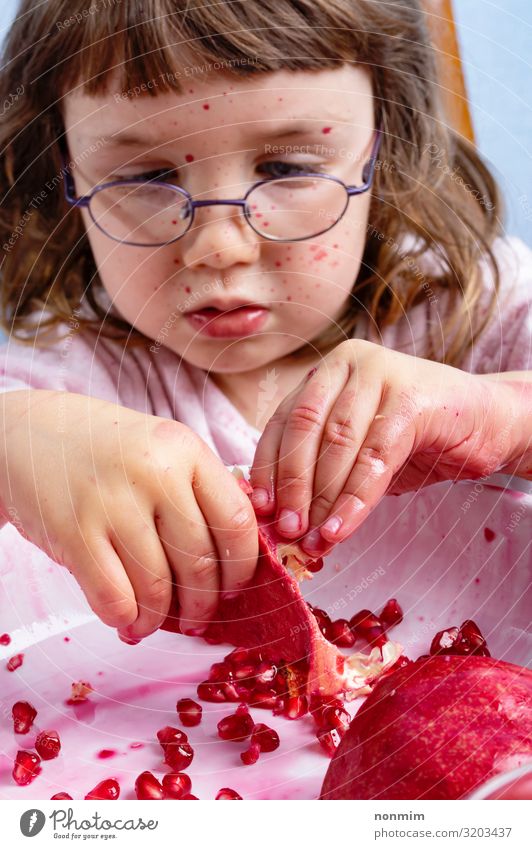 Girl peel pomegranate. Face dirty of red spots Fruit Dessert Nutrition Vegetarian diet Child Eyeglasses Dirty Fresh Natural Curiosity Juicy Red Concentrate
