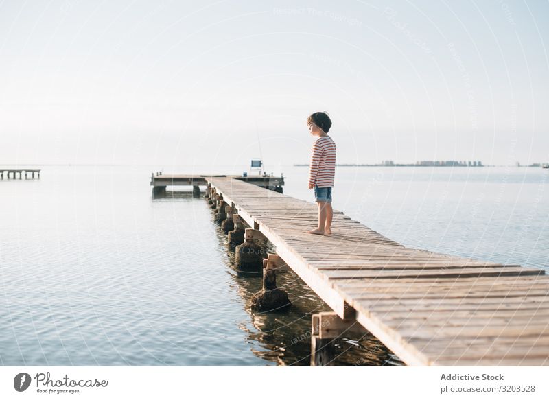 Lonely kid on pier in sunshine Boy (child) Jetty Dream Child Summer Sunlight Vacation & Travel Infancy Water Nature Leisure and hobbies Trip Intellect