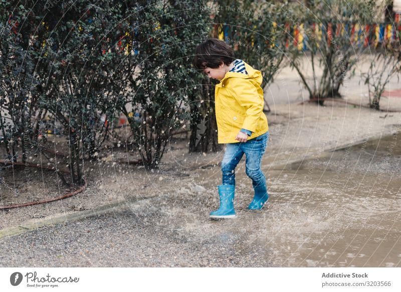 Happy kid jumping on puddle Boy (child) Puddle Jump Joy Street gumboots Wet Water Child Playful Infancy Autumn Weather Nature Rubber Playing Raincoat