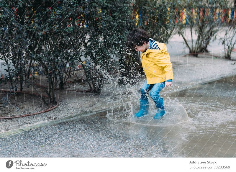 Happy kid jumping on puddle Boy (child) Puddle Jump Joy Street gumboots Wet Water Child Playful Infancy Autumn Weather Nature Rubber Playing Raincoat
