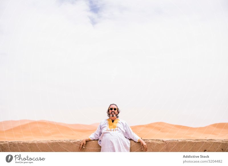 Cheerful adult man in desert Man Portrait photograph Looking into the camera Lean Balcony Desert Morocco Vacation & Travel Vantage point Landscape Heat Exotic