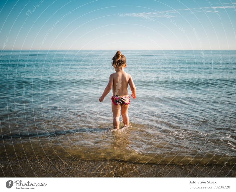 Back view of girl standing in water of seaside Girl Water Playing Cute Toddler Delightful Ocean swimming suit Warmth Beach Sunbeam Infancy Swimming & Bathing