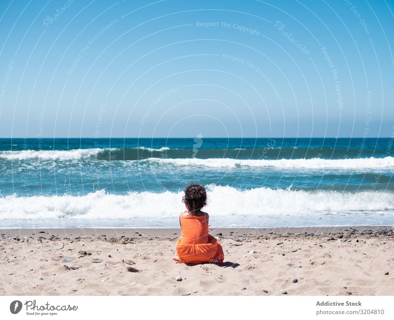 Little girl sitting on beach and admiring view Girl Beach Child Sit Vantage point seaside Sand Ocean Sky Small Woman Orange Dress Looking Beautiful Summer Wave