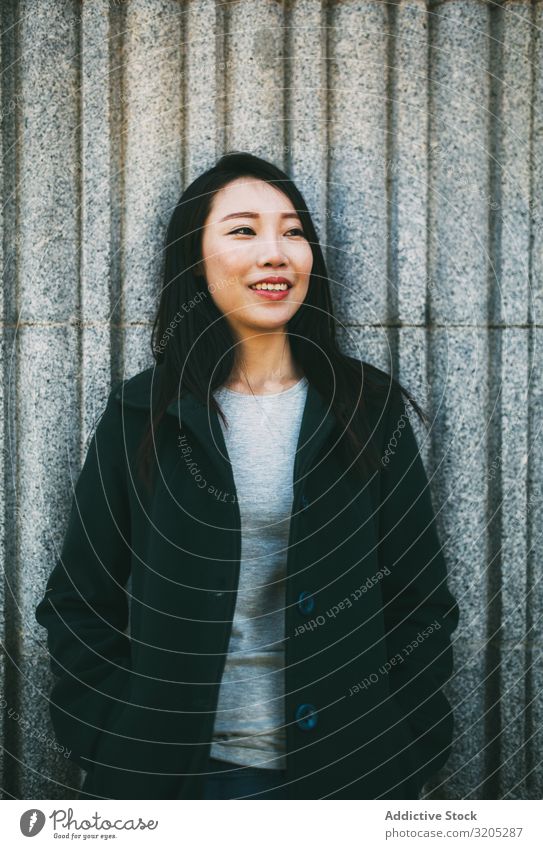 Asian woman near marble wall Woman Wall (building) Lean asian Smiling Youth (Young adults) Street City Marble Building Elegant Coat Style Hip & trendy Easygoing