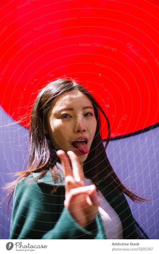 Asian woman showing tongue and V sign Woman v sign Gesture Bright Wall (building) Town City Street asian Youth (Young adults) Funny two fingers Peace Success
