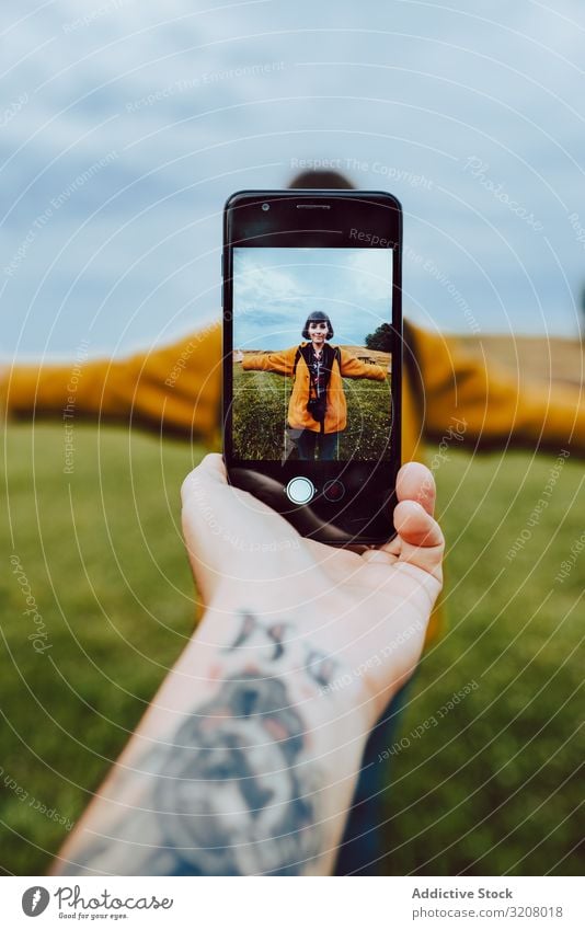 Crop hand taking photo of woman in field smartphone tattoo outstretched arms freedom lifestyle leisure travel trip journey weekend mobile technology device