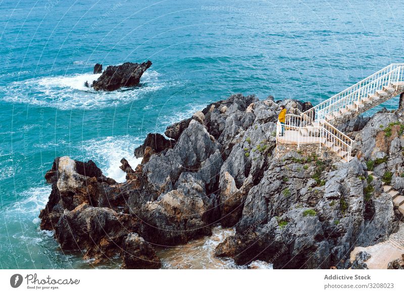 Woman looking at waving sea from steps woman admire waves bay cliff stairway water nature shore female travel trip journey tourism view ocean storm weather