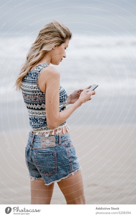 Pretty female talking on mobile phone woman smartphone sea beach summer vacation travel communication holiday young attractive beautiful blonde casual stylish