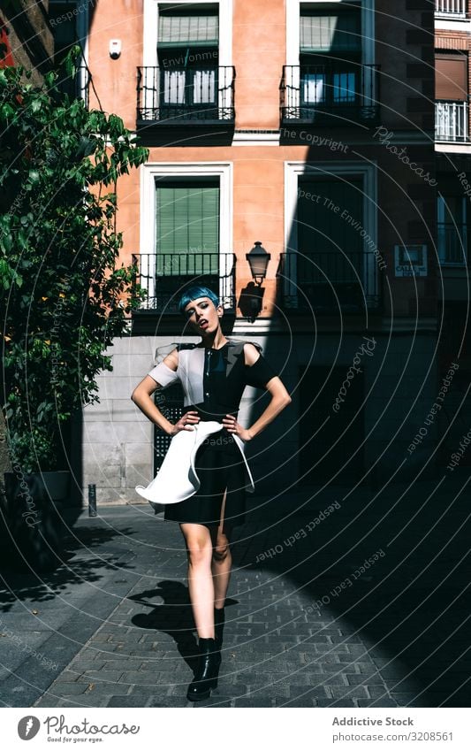 Confident lady in futuristic dress on street woman city trendy model fashion contrast confident vogue buildings pavement hands on waist young style female
