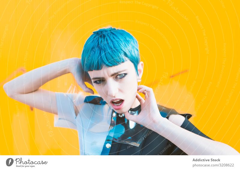 Alternative model portrait against yellow wall woman futuristic alternative dress blue hair informal pavement glamour lady young expression vogue female beauty