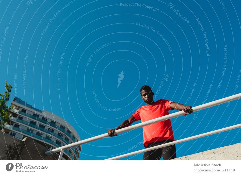 African American young man on bridge under blue sky urban sportive inspiration determined healthy muscular ethnic black african american geometric contemplate