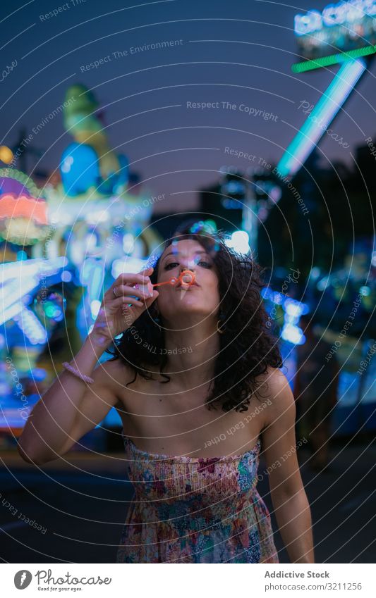 Woman in amusement park blowing bubbles woman summer fun leisure female brunette enjoy young evening beautiful holiday vacation attraction entertain sundress