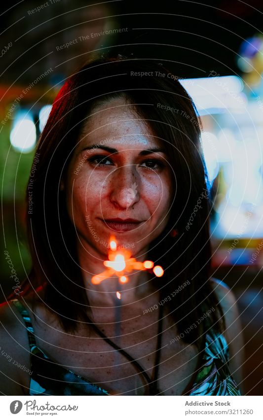 Woman holding sparkler on fairground in evening woman portrait summer vacation celebrate funfair smile young female brunette mysterious enjoy beautiful natural