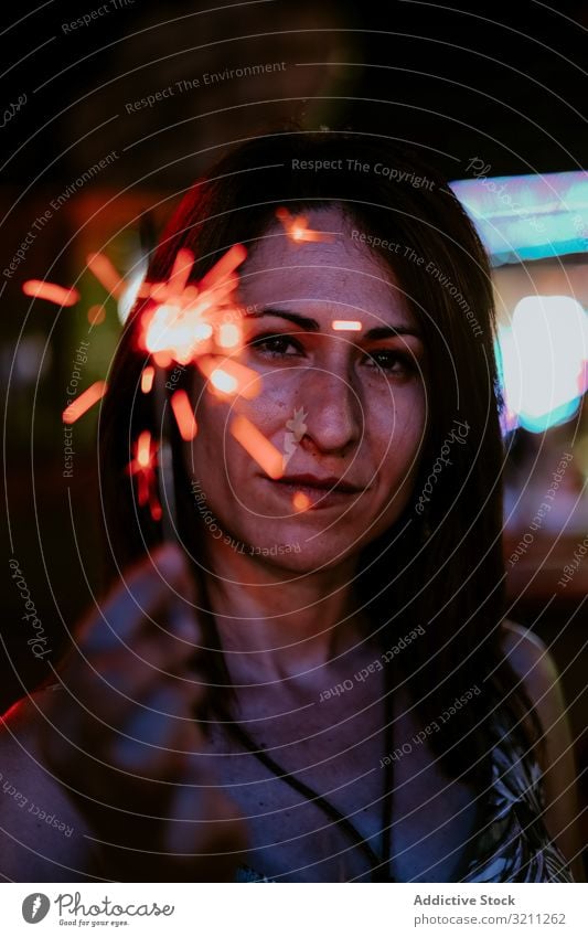 Woman holding sparkler on fairground in evening woman portrait summer vacation celebrate funfair smile young female brunette mysterious enjoy beautiful natural
