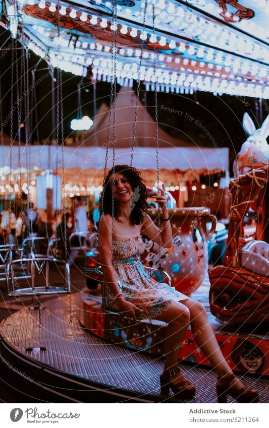 Woman enjoying ride on carousel woman amusement park summer cheerful evening fun leisure female brunette happy young beautiful holiday dress attraction