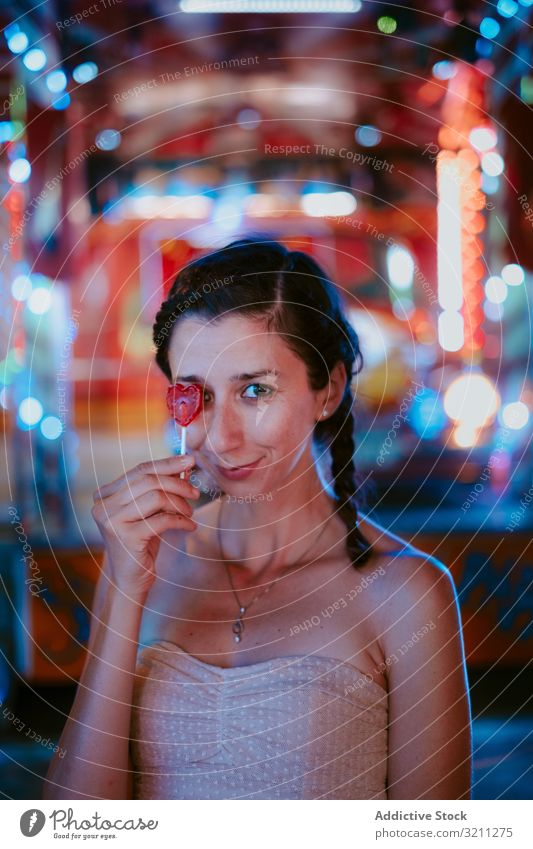 Woman with lollipop in amusement park woman funfair relax summer cheerful smile leisure female evening dark enjoy happy casual young beautiful holiday