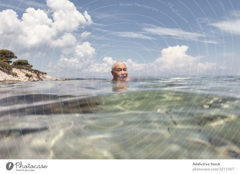 Cheerful elderly man swimming in sea water vacation senior crystal retired travel leisure greece halkidiki ocean mature happy floating nautical summer enjoy